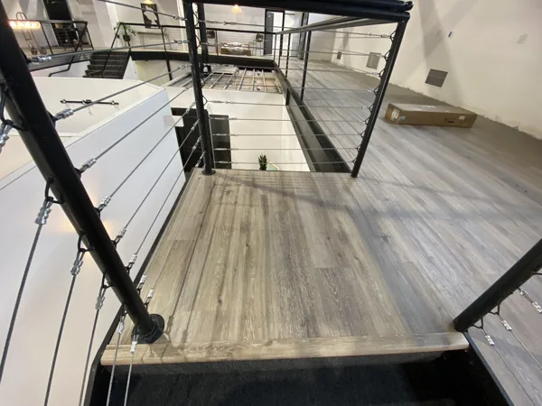 A wider view of the landing, railing posts and adjoining stairs.