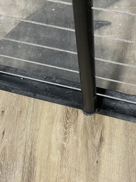 The plank landing meets the stair edge beside the railing post, bringing the adjoining surfaces together.