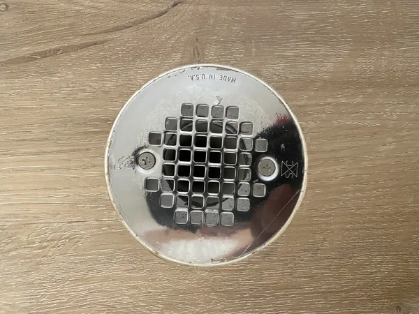 Carefully shaped plank cuts follow the drain opening. This close-up shows the fitted edge around the cover.