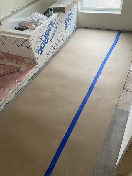 Protective paper and taped seams cover the floor during ongoing construction.