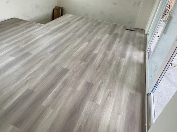 Wood-look plank flooring across the room near the walls and window.