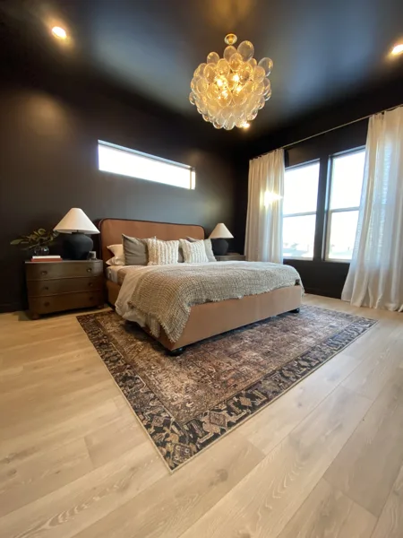 Laminate flooring around the bedroom rug and bed.