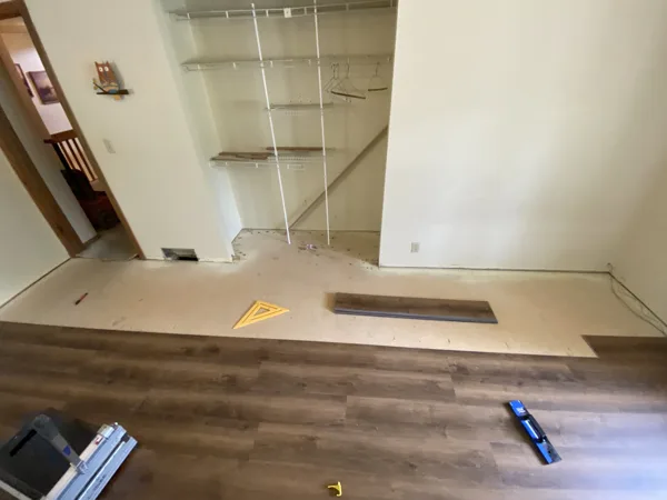Plank flooring and installation work in the office around the desks and shelving.