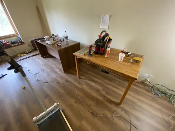 Plank flooring and installation work in the office around the desks and shelving.