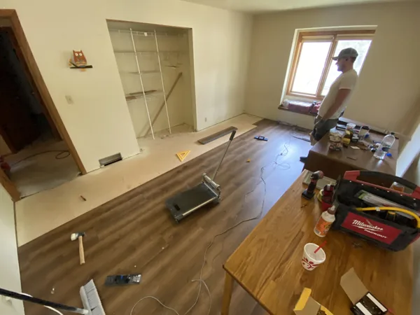 Plank flooring and installation work in the office around the desks and shelving.