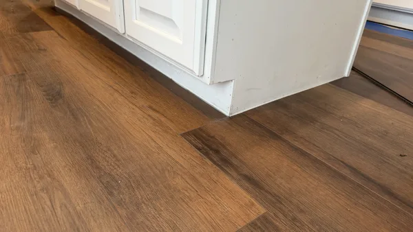 A close view of the flooring edge at the kitchen cabinetry. Product-specific expansion requirements must be reviewed for each installation.